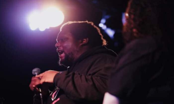 Man on stage talking into microphone at an event