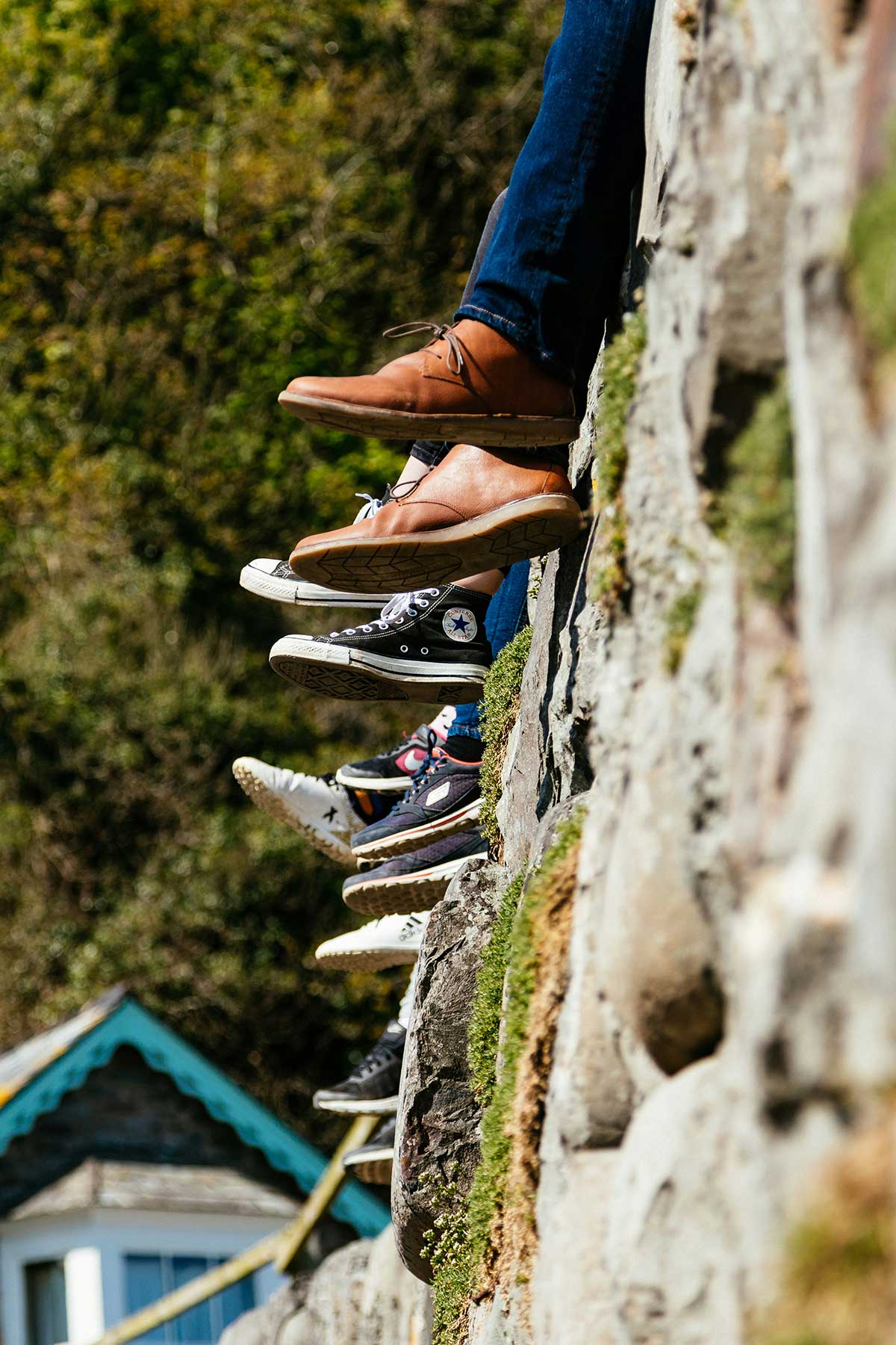 Youth sitting on large rock formation with their feet hanging down