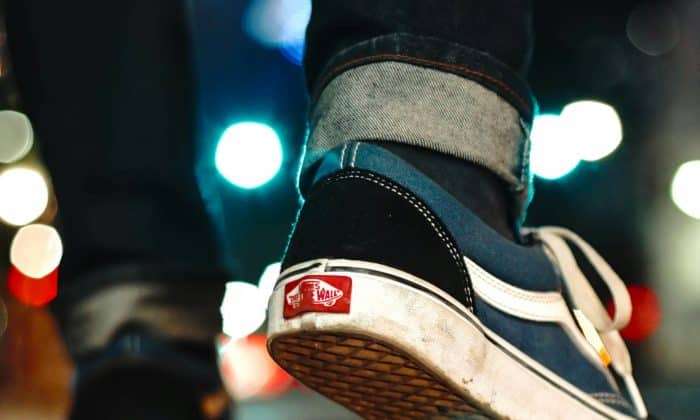 A close up photo of a youth walking in skateboard shoes