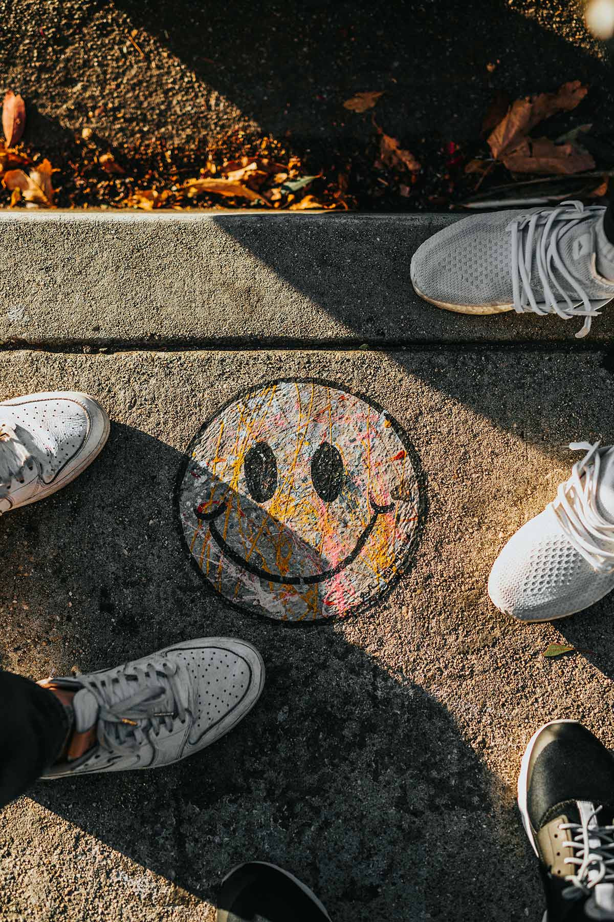 Youth with feet pointing at each other in circle with a chalk smiley face drawn on the sidewalk