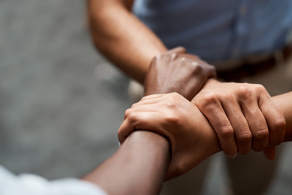 Three people holding hands in support of one another