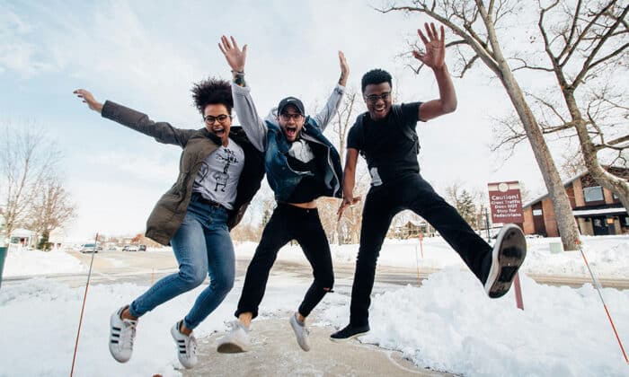 Three youth outside in winter jumping and smiling